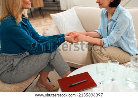 Female psychologist holding woman's hands helps in personal therapy session, psychologist or counselor showing understanding and caring, supporting depressed client in treatment. Royalty-Free Stock Photo #2135896397