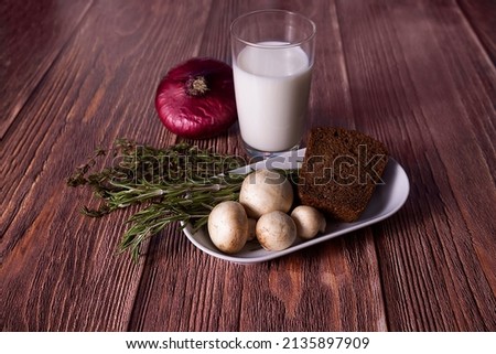Sliced bread, mushrooms, onions and glass of milk.