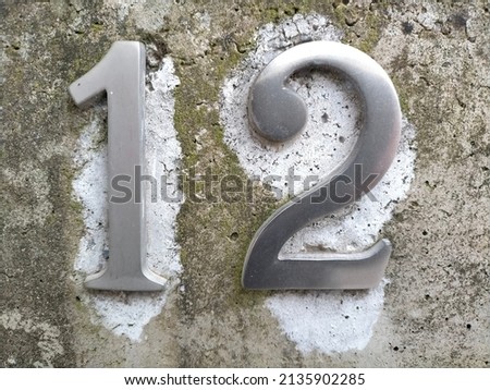 Number twelve in metal, 12 on a wall at the entrance of a house.