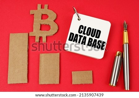 Business and bitcoin concept. On a red surface lie a bitcoin symbol, a graph, a pen and a notepad with the inscription - Cloud data base