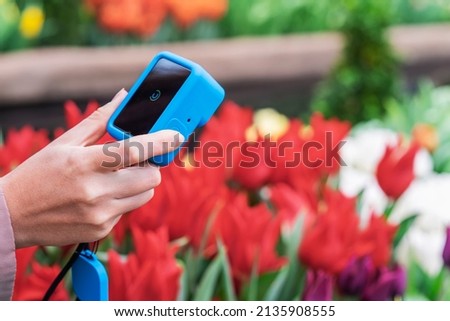 Hands of Girl using compact camera to take photo of flowers in park. Modern technology and nature Royalty-Free Stock Photo #2135908555