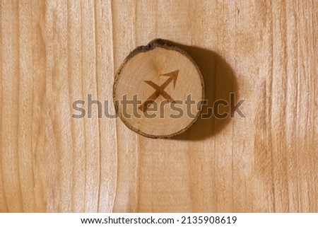 Close-up shot of a piece of wood with a zodiac sign engraved on it, especially the sagittarius sign