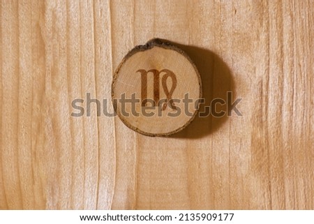 Close-up shot of a piece of wood with a zodiac sign engraved on it, especially the virgo sign