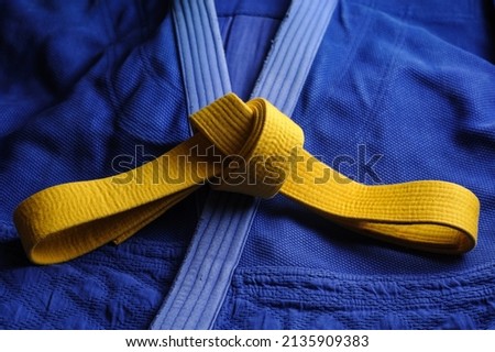 Yellow judo belt on a blue kimono. Colors of the Ukrainian flag Royalty-Free Stock Photo #2135909383