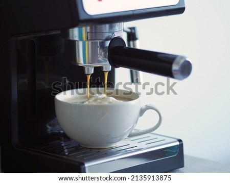 Close-up image of iced cream coffee from machines percolator. Drink flowing cappuccino cup that is prepar service Coffee aroma bake shop, home atmosphere look warm of espresso pouring