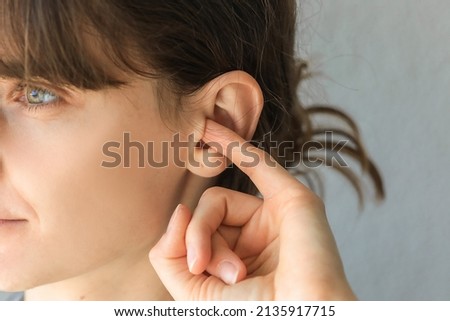 Woman putting a finger into her ear.  Itchy ear isolated with copy space. otitis media Royalty-Free Stock Photo #2135917715