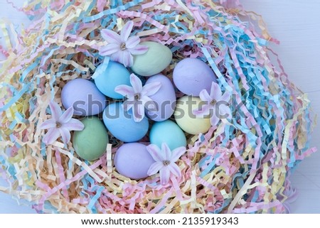 Delicate Easter picture. There are colorful quail eggs and pink flowers in the nest. View from above. Delicate pastel shades