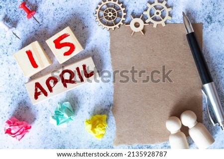 A wooden calendar with the date April 15 on the desktop.