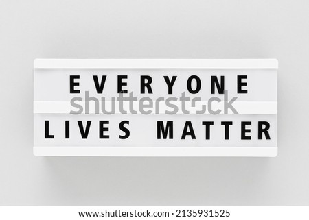 EVERYONE LIVES MATTER written in a lightbox on a gray background. Top view, copy space