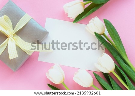 Blank sheet, gift box and white tulips on pink background. Women's day, Mother's day concept. Top view, flat lay, mockup