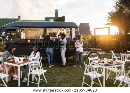 Multiracial people ordering gourmet food in front of take away restaurant truck outdoor - Soft focus on african man face Royalty-Free Stock Photo #2135934023