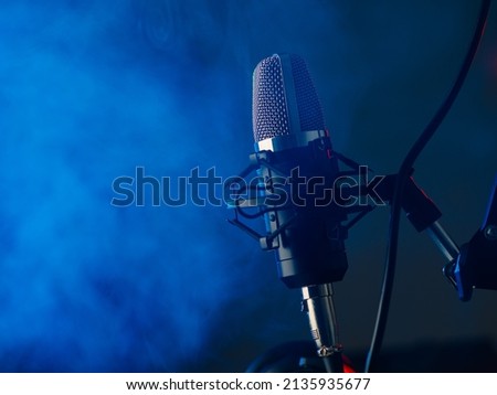 Studio microphone on blue smoke background. Vocal, blogger and sound recording concept.Background for karaoke and recording studio