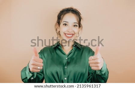 Young woman on green shirt doing ok good sign with hands, happy about the outcome. Young woman attitude. Soft tone color background, expression of normal people. Mockup concept with people