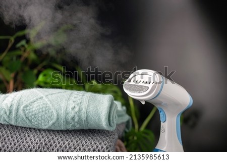 Portable home and travel garment steamer for clothes. Clothes pile. Housework Royalty-Free Stock Photo #2135985613