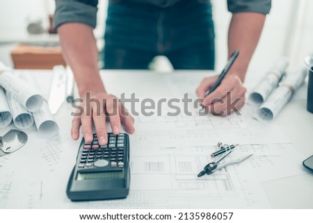 Architect engineer use calculator for calculate drawing design working on blueprint. House planning design and construction concept.