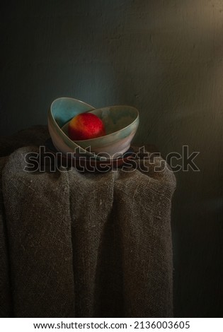 Red ripe apple in a green ceramic bowl on a dark background. Minimalism. Vintage.