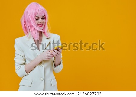 cheerful glamorous woman pink wig talking on the phone yellow background Royalty-Free Stock Photo #2136027703