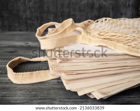 Stack of newspapers on a wooden background. Reusable eco-friendly mesh bag