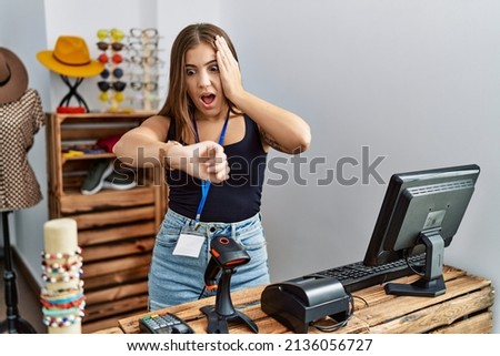 Young brunette woman holding banner with open text at retail shop looking at the watch time worried, afraid of getting late 