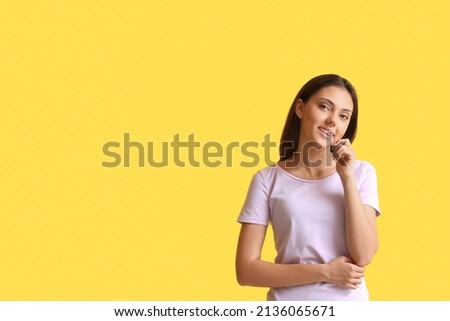Pretty teenage girl with dental braces on yellow background
