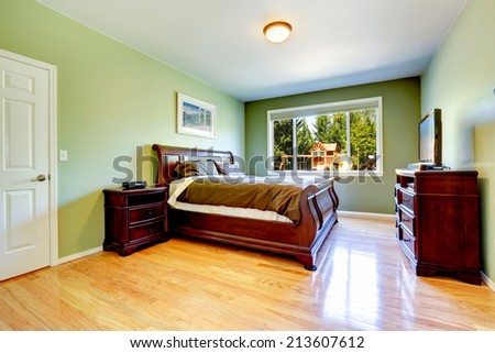 Light green bedroom with hardwood floor and carved wood furniture