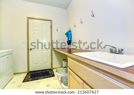 Simple laundry room with brown counter top and sink