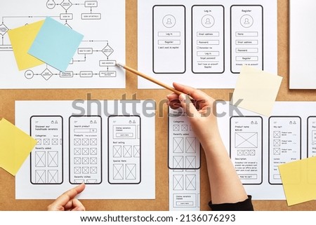 Web UX designer working on mobile responsive website. Flat lay image of numerous app wireframe sketches and user flow over product designer desk.  Royalty-Free Stock Photo #2136076293