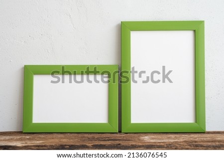 Empty two green photo frame on old wooden table over white wall background copy space. Home decoration, creative idea design concept.