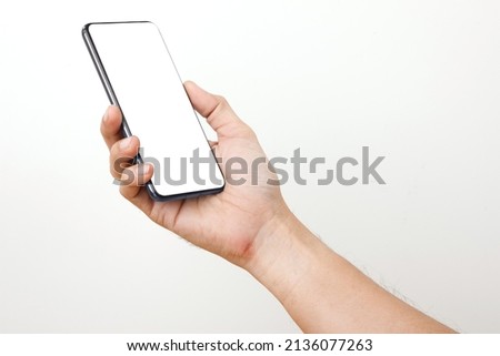 Side View of Man Holding Smart phone . Cell phone in Man hand on a white background With white display for COPY SPACE. Royalty-Free Stock Photo #2136077263