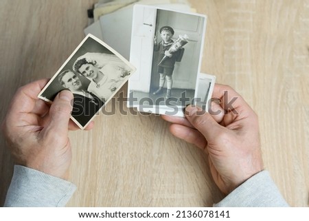 closeup male hand holding old vintage photos of 1940-1950, concept of family tree, genealogy, childhood memories, memory of ancestors
