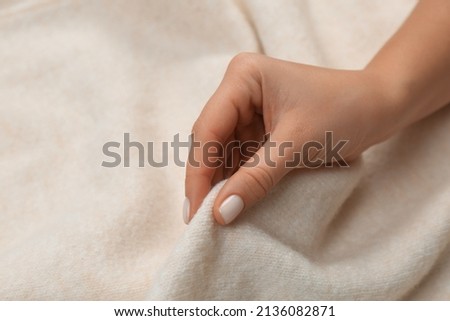 Woman touching soft beige knitted fabric, closeup Royalty-Free Stock Photo #2136082871