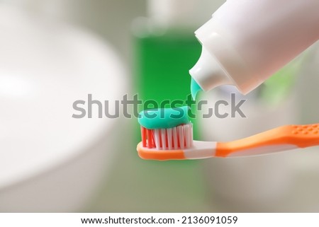 Applying toothpaste on brush against blurred background, closeup
