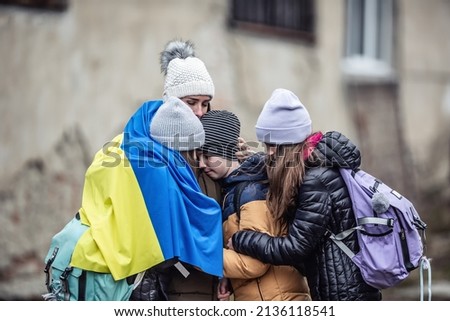 Ukrainian woman holds her three children all sad from being forced to flee their home country and become refugees. Royalty-Free Stock Photo #2136118541