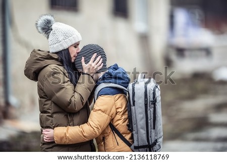 Woman kisses her boy on forehead outdoors as they both stay in the war zone after Russia attacked Ukraine. Royalty-Free Stock Photo #2136118769