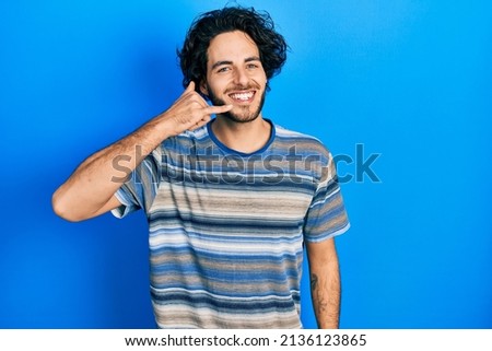 Handsome hispanic man wearing casual clothes over pink background smiling doing phone gesture with hand and fingers like talking on the telephone. communicating concepts. 