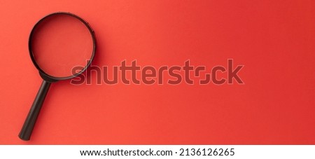 Photo of magnifying glass on left side over red background with copyspace for put your text or logo.,Flat lay top view mock-up item concept.
