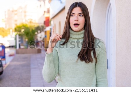 Young Brazilian woman at outdoors thinking an idea pointing the finger up