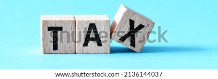 TAX text on wooden cubes on blue background. Tax Business Concept .