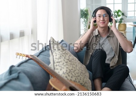 An asian man is listening Music in living room . 
