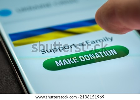 Close-up finger pressing make donation button on smartphone screen. Donation money online concept