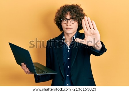Handsome young man working using computer laptop with open hand doing stop sign with serious and confident expression, defense gesture 