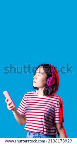 Young asiatic woman isolated listening music holding smartphone wireless headphones - advertising copyspace