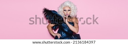 blonde and eccentric drag queen showing hush sign and looking at camera on pink, banner Royalty-Free Stock Photo #2136184397