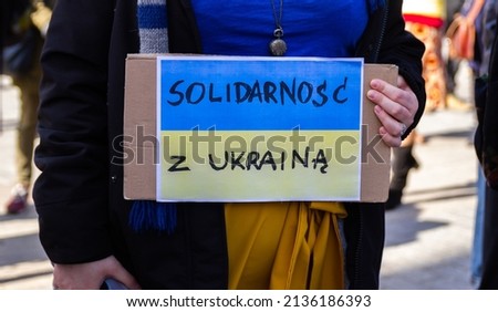 Placard saying "Solidarity with Ukraine" in Polish language, on the Ukrainian flag in protest manifestation against war, Russia attack on Ukraine. Russian invasion, anti-war demonstration.