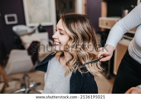 Beautiful young woman with perfect hairstyle satisfied after dyeing hair and making highlights in hair salon. Royalty-Free Stock Photo #2136195021
