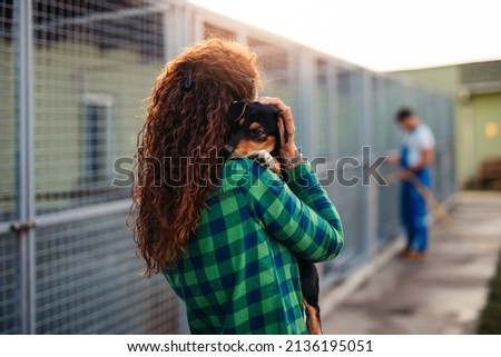Young adult woman holding adorable dog in animal shelter. Royalty-Free Stock Photo #2136195051