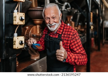 Mature man is working in coffee roasting shop.