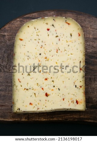 the best delicious soft gourmet cheese slice of the wheel from Holland the Netherlands with peppers and herbs with dark moody background. food photography stock image Royalty-Free Stock Photo #2136198017
