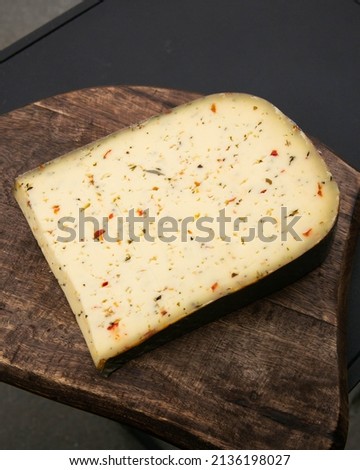 the best delicious soft gourmet cheese slice of the wheel from Holland the Netherlands with peppers and herbs with dark moody background. food photography stock image Royalty-Free Stock Photo #2136198027