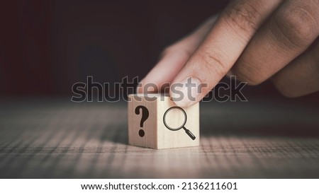 Hand flip magnifying glass and question mark sign icon in wooden cube. Problems and root cause analysis concept. copy space for background or text. Royalty-Free Stock Photo #2136211601